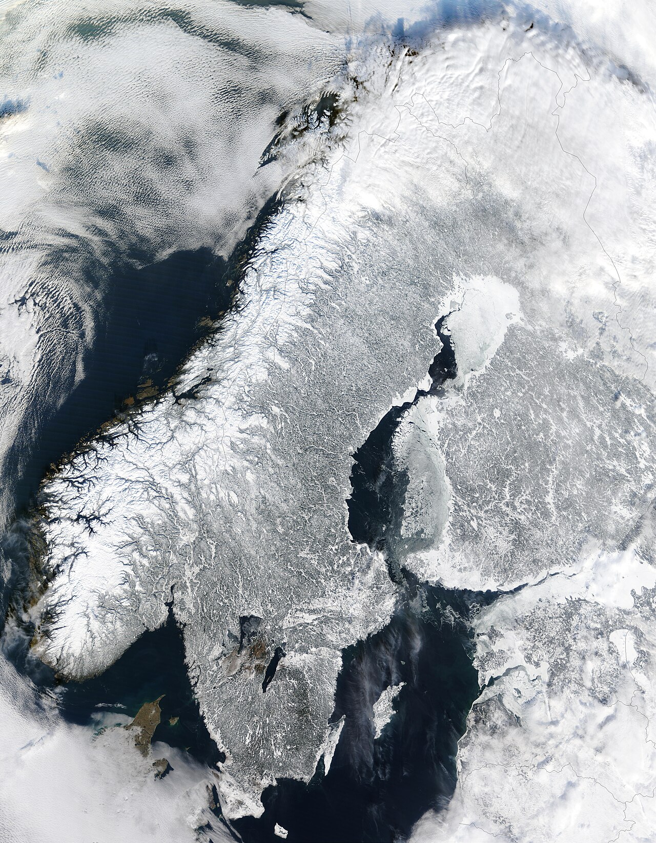 Satellite image of Scandinavia in winter showing Norway's fjords along the coast.