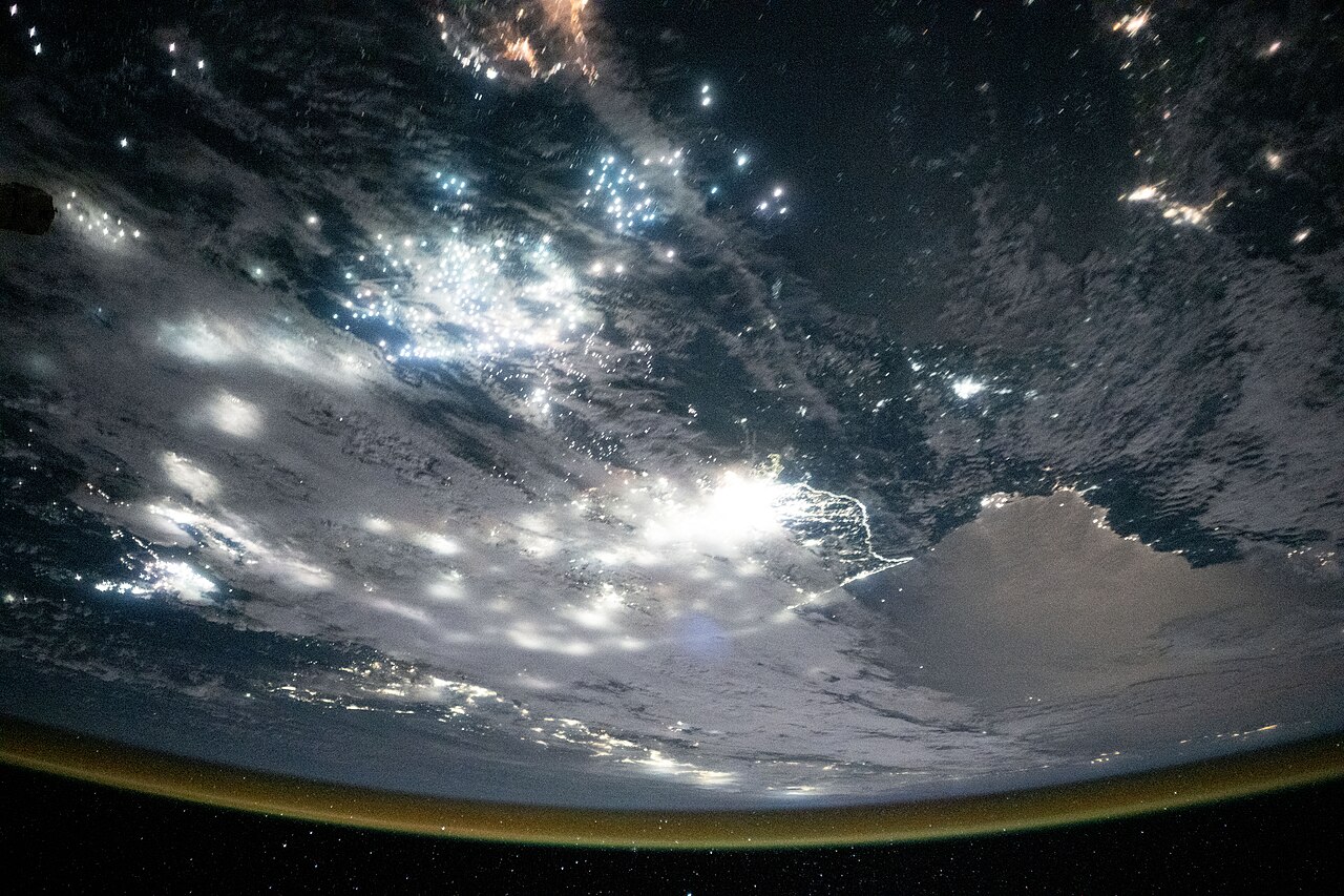 Contains modified NASA imagery from the International Space Station showing the well-lit border between South Korea and the less-illuminated North Korea, with the Sea of Japan and Yellow Sea visible.