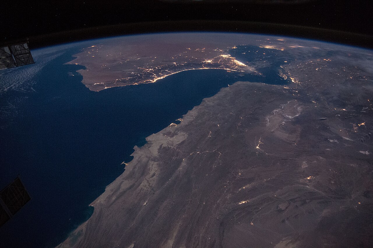 The Strait of Hormuz at night, showing city lights along the coasts of Oman, Iran and the UAE.